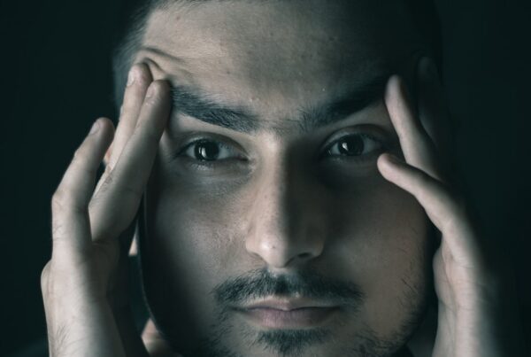 Ein Mann blickt nachdenklich nach vorne und hält seine Hände an die Schläfen – symbolisch für neurologische Beschwerden oder mentale Erschöpfung, wie sie bei Neurozöliakie auftreten können.